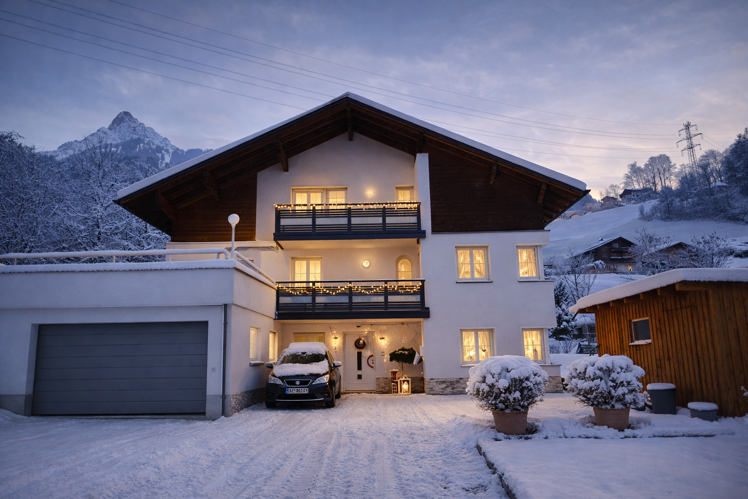 Ferienwohnung Haus Bergharmonie Tschagguns Montafon im Winter – verschneite Außenansicht mit Lichterketten und Bergpanorama