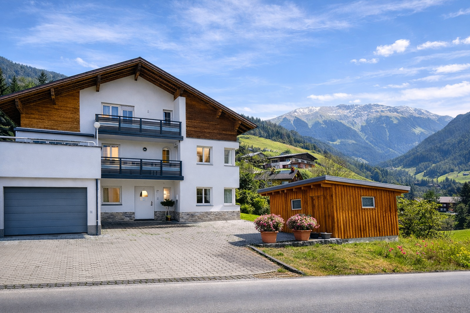 Ferienwohnung Haus Bergharmonie in Tschagguns Montafon im Sommer – Außenansicht mit Bergpanorama und blauem Himmel