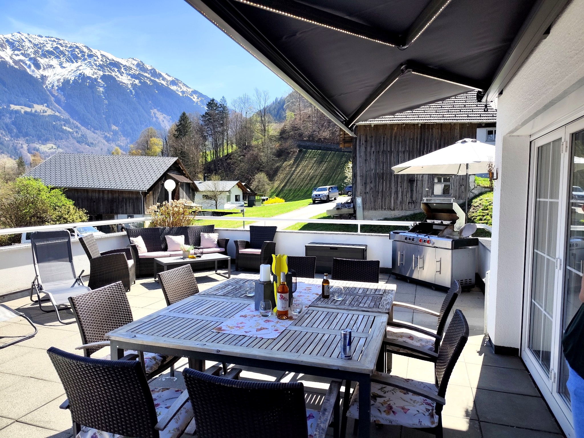 Terrasse Ferienwohnung Haus Bergharmonie Tschagguns – Essbereich mit Markise, Gasgrill und Bergpanorama Montafon
