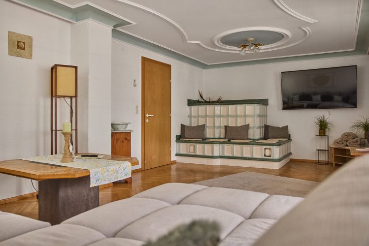 wohnzimmer-kachelofen-fernseher-panorama-blick-haus-bergharmonie-tschagguns-montafon